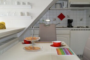 A kitchen with a white countertop, a coffee maker, and a red kettle. - Hüs am a Süüd Ferienwohnung Ley (Dunsum)