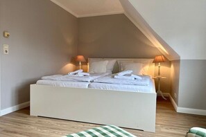 A neatly made bed with folded towels, a bedside lamp, and a checkered throw on the floor. - Holiday home in Nieblum with swimming pool (Nieblum)