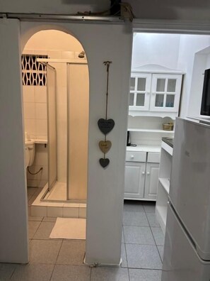 Una cocina con armarios blancos, un refrigerador y una ventana.