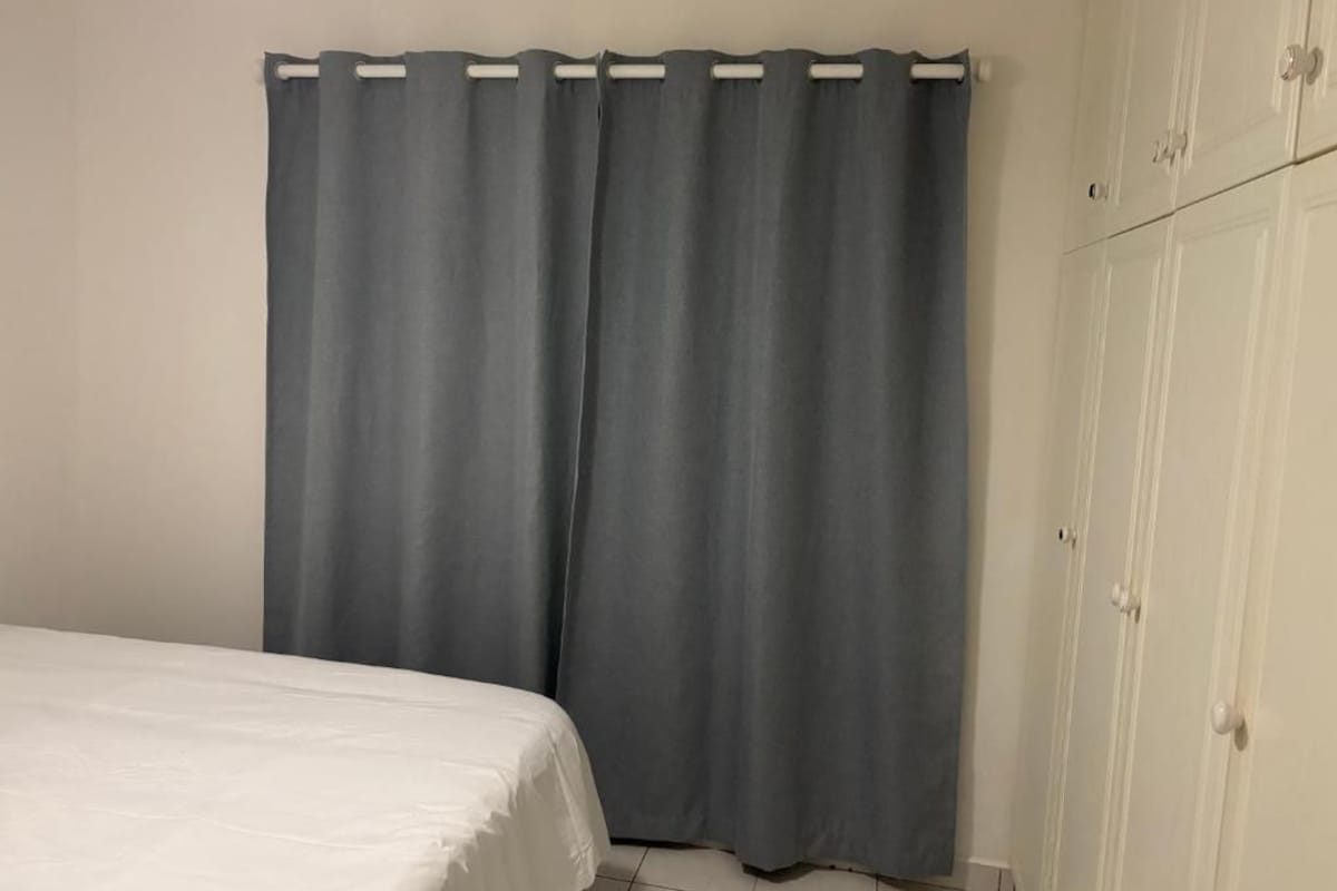 Ein Schlafzimmer mit einem Bett, einem grauen Vorhang und einem Kleiderschrank.