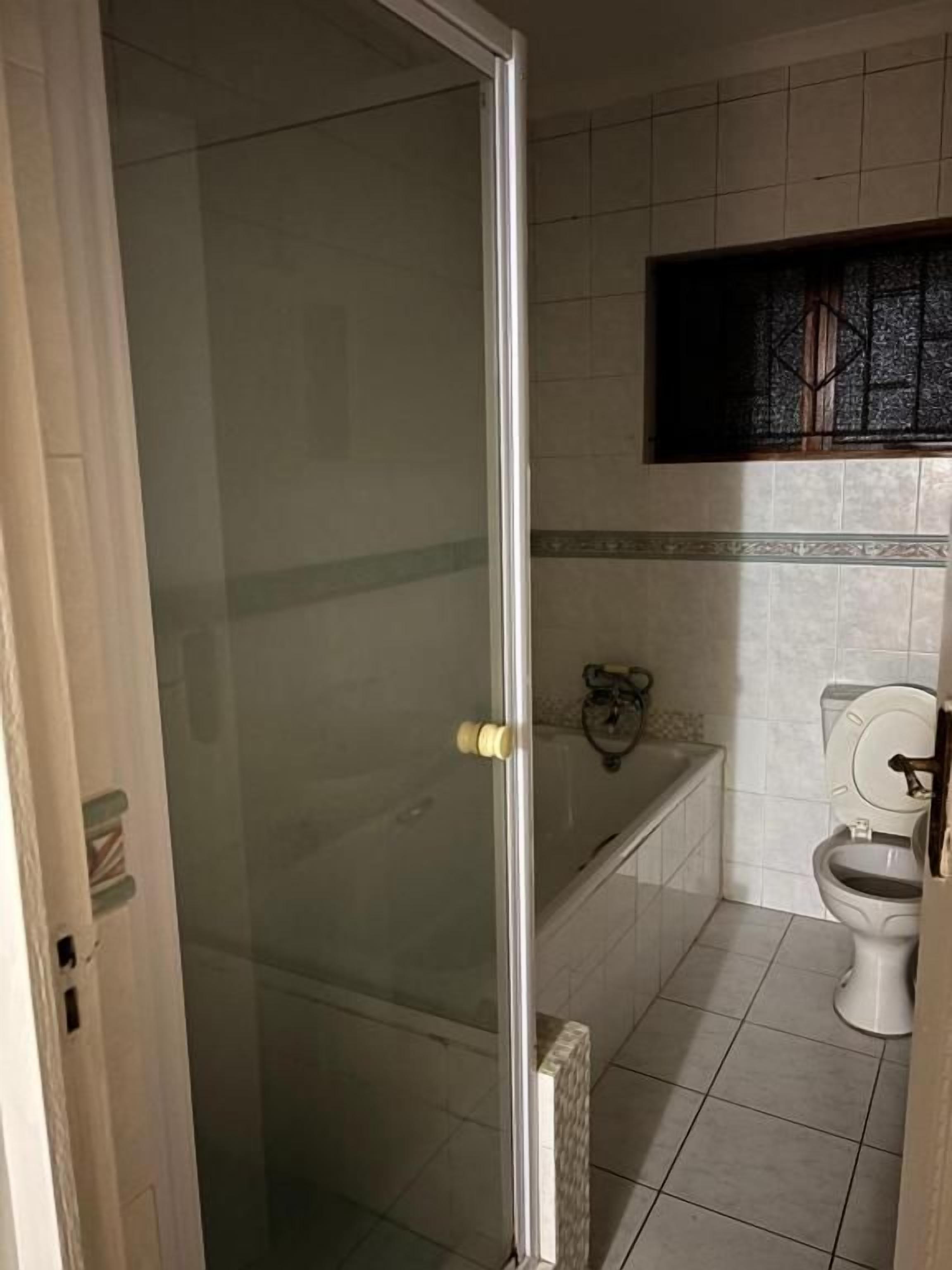 A bathroom with a glass shower enclosure, a toilet, and a bathtub.