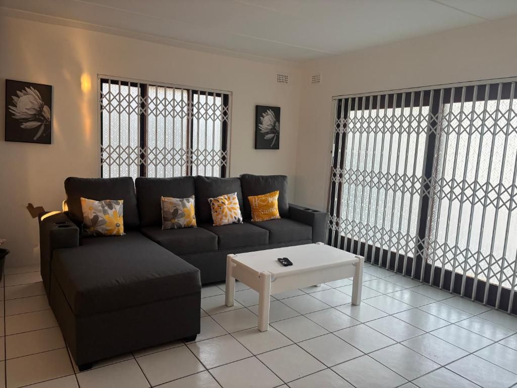 A living room with a sectional sofa, a coffee table, and large windows with metal bars.