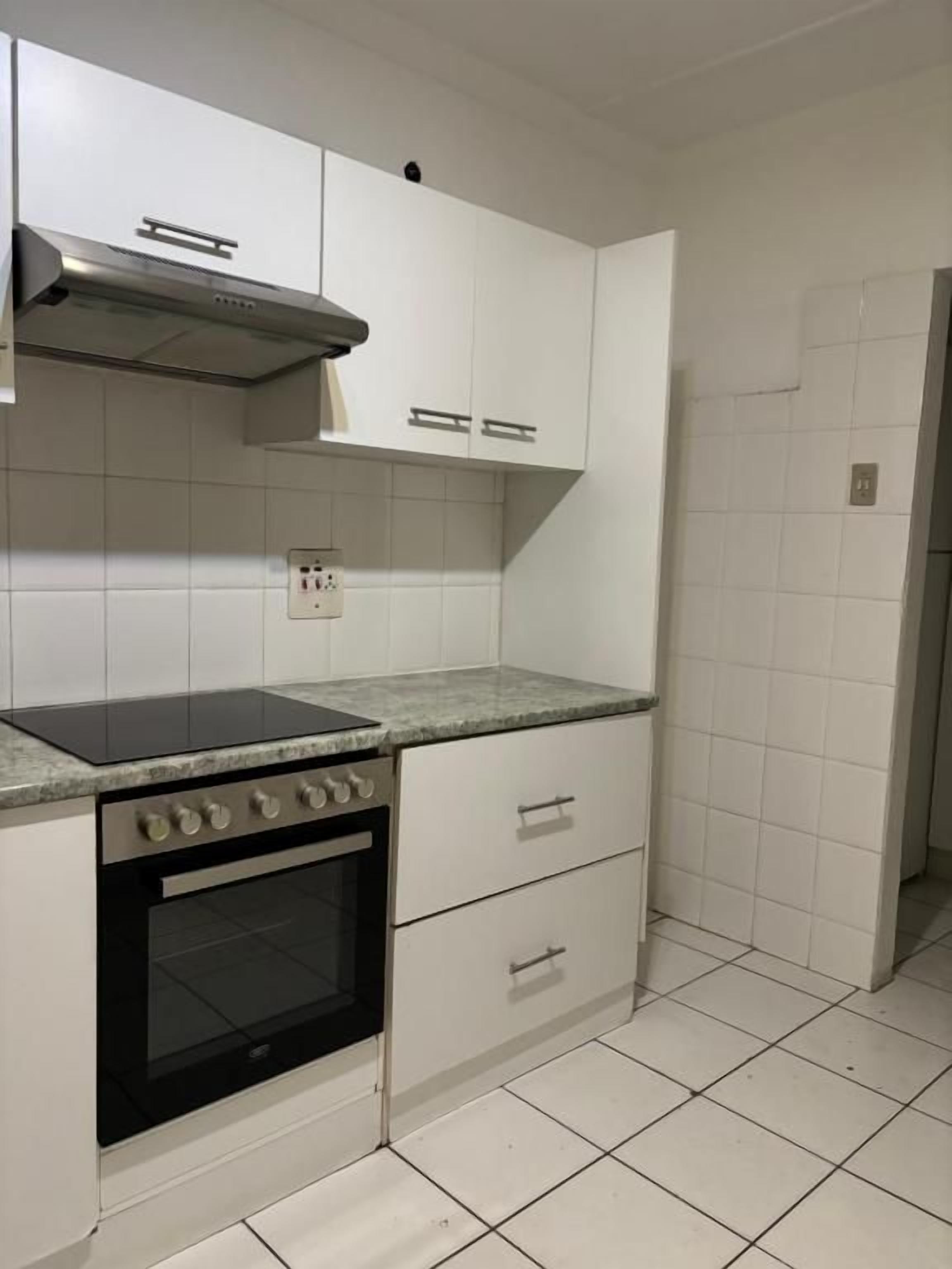 A kitchen with white cabinets, a stainless steel range hood, a black oven, and a granite countertop.