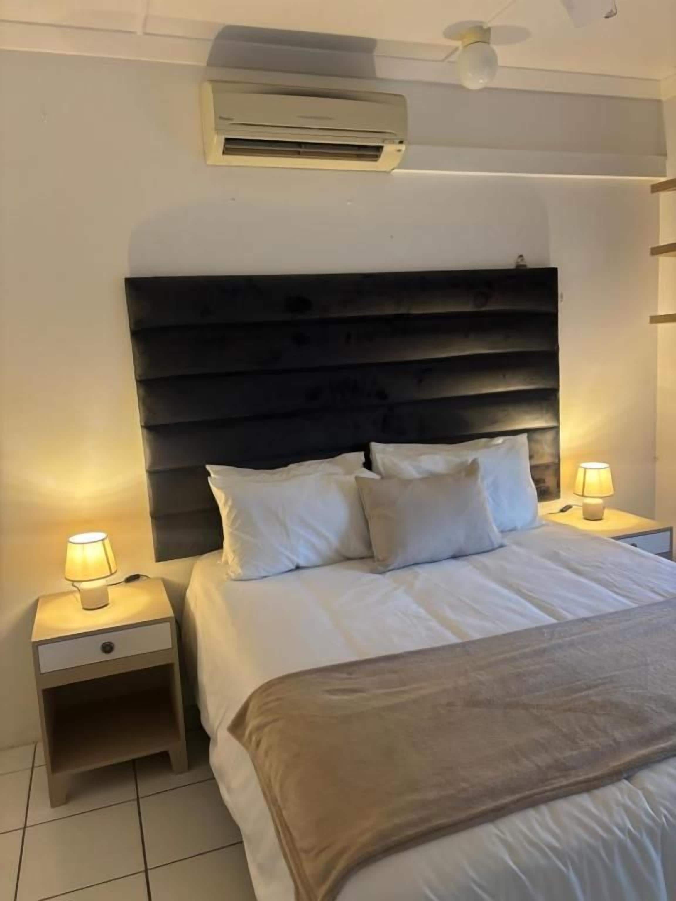 Une chambre d’hôtel équipée d’un lit, de lampes de chevet, d’une table de chevet et d’un appareil de climatisation.
