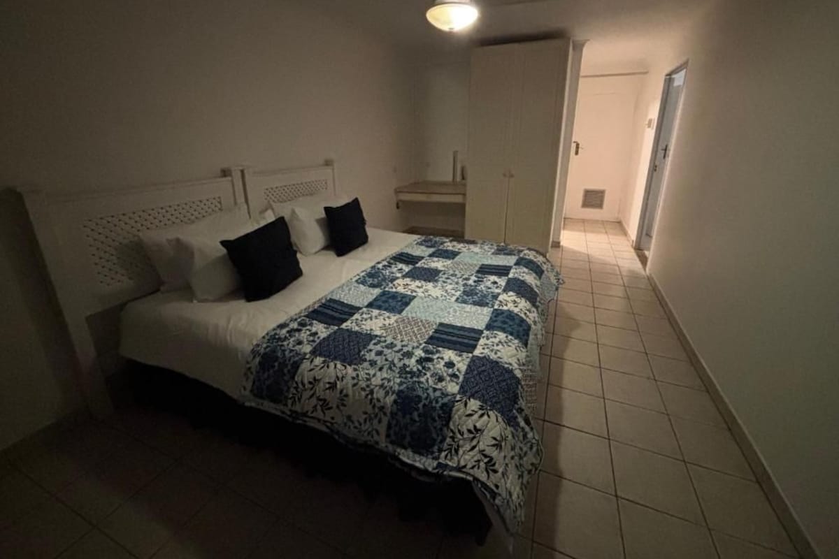 Ein Schlafzimmer mit einem Bett, einem Deckenventilator und einer Tür zu einem anderen Raum.