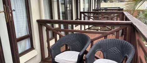 A balcony with wicker chairs and a wooden railing.