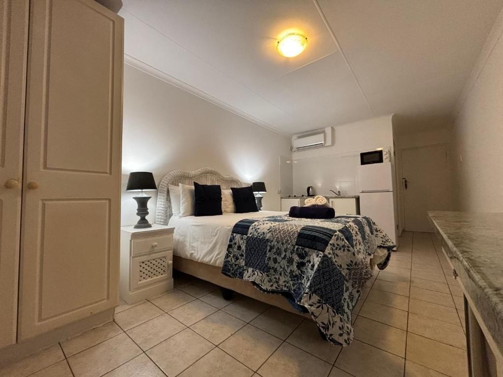 A bedroom with a bed, nightstands, a lamp, a dresser, and an air conditioning unit.