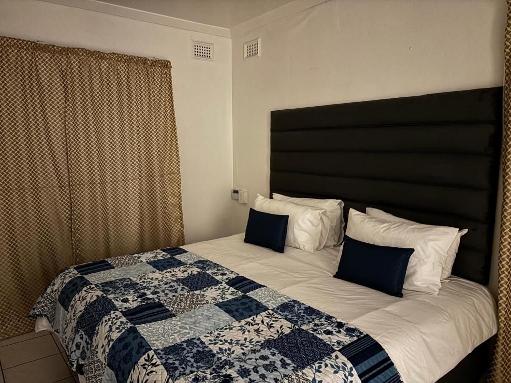 A hotel room with a bed, a headboard, and a window with curtains.