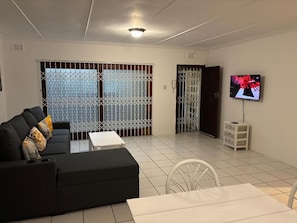 A living room with a sofa, a TV, a table, and a chair.