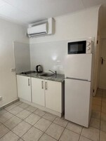 Una cocina compacta con microondas, pileta y un refrigerador pequeño.