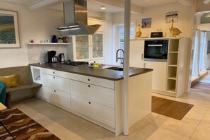 Une cuisine moderne dotée d’un îlot central, de meubles blancs et d’un four encastré.