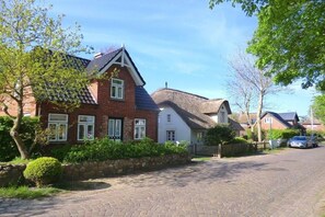 Une rue résidentielle bordée de maisons, avec une allée pavée et une voiture garée.