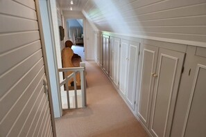 En hall med en träbänk, vita dörrar och ett golv täckt av matta.