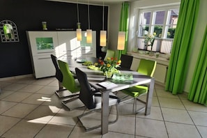 A modern dining area with a table, chairs, and a view of the outdoors. - Holiday home in Nieblum with swimming pool (Nieblum)
