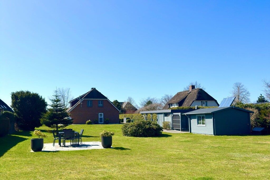 A residential property with a lawn, a patio with outdoor furniture, and a small shed.