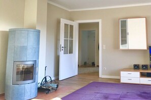 Una habitación con chimenea empotrada, una puerta que da a otra estancia, un espejo y un mueble pequeño con altavoces.