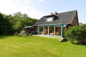 A house with a conservatory, a lawn, and a garden. - Haus Heike - Holiday Apartment Ground Floor (Utersum)