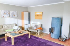 Ein Wohnzimmer mit Sofa, Sessel, Couchtisch, Kamin und Kunstwerken an den Wänden.