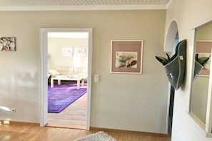 An interior space with a doorway leading to another room, a white wall with a framed picture, and a gray object on the wall. - Haus Heike - Holiday Apartment Ground Floor (Utersum)