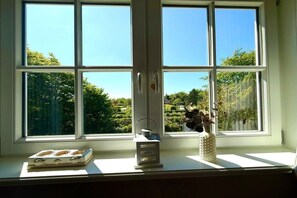 A window with a view of a garden and a white wall. - Haus Heike - Holiday Apartment 1st Floor (Utersum)