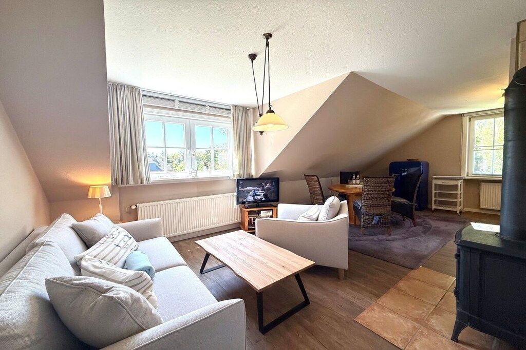 A cozy living room with a sofa, a coffee table, a TV, and a fireplace.