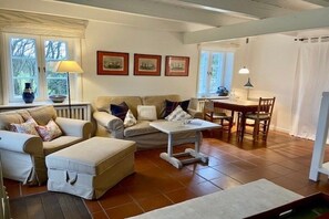 A living room with a sofa set, a coffee table, and a dining table with chairs. There are framed pictures on the wall and a lamp on the table. - Dream Street Bollis Huis 2 (Nieblum)