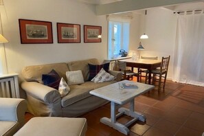 A living room with a sofa, a coffee table, a dining table with chairs, and framed pictures on the wall. - Dream Street Bollis Huis 2 (Nieblum)
