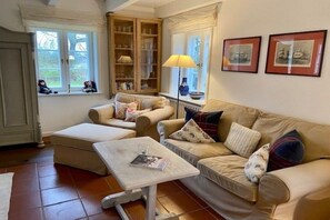 En hyggelig stue med en sofa, skammel og et bord med en lampe.