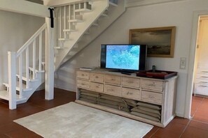 A staircase with white railings, a television on a wooden cabinet, and a painting on the wall. - Dream Street Bollis Huis 2 (Nieblum)