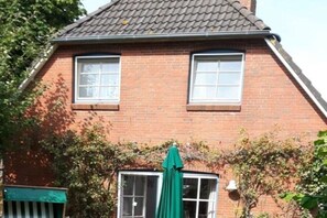 Ein Backsteinhaus mit zwei Fenstern und einem grünen Regenschirm.