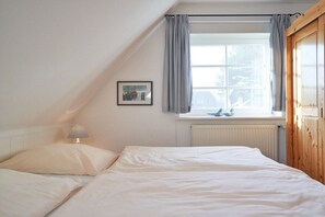 A bedroom with a bed, a window with curtains, a radiator, and a picture on the wall. - Holiday home with 1 bedroom (Wrixum auf Föhr)