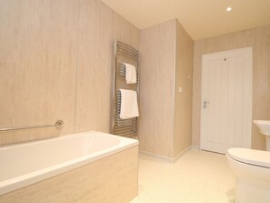A bathroom with a bathtub, a toilet, and a towel rack. - Elm Cottage (Truro)