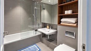 A modern bathroom with a glass-enclosed shower, a white sink, and a wooden shelf with towels. - Southeast London 3-bed Apt, Sleeps 6 w Lake Access (London)