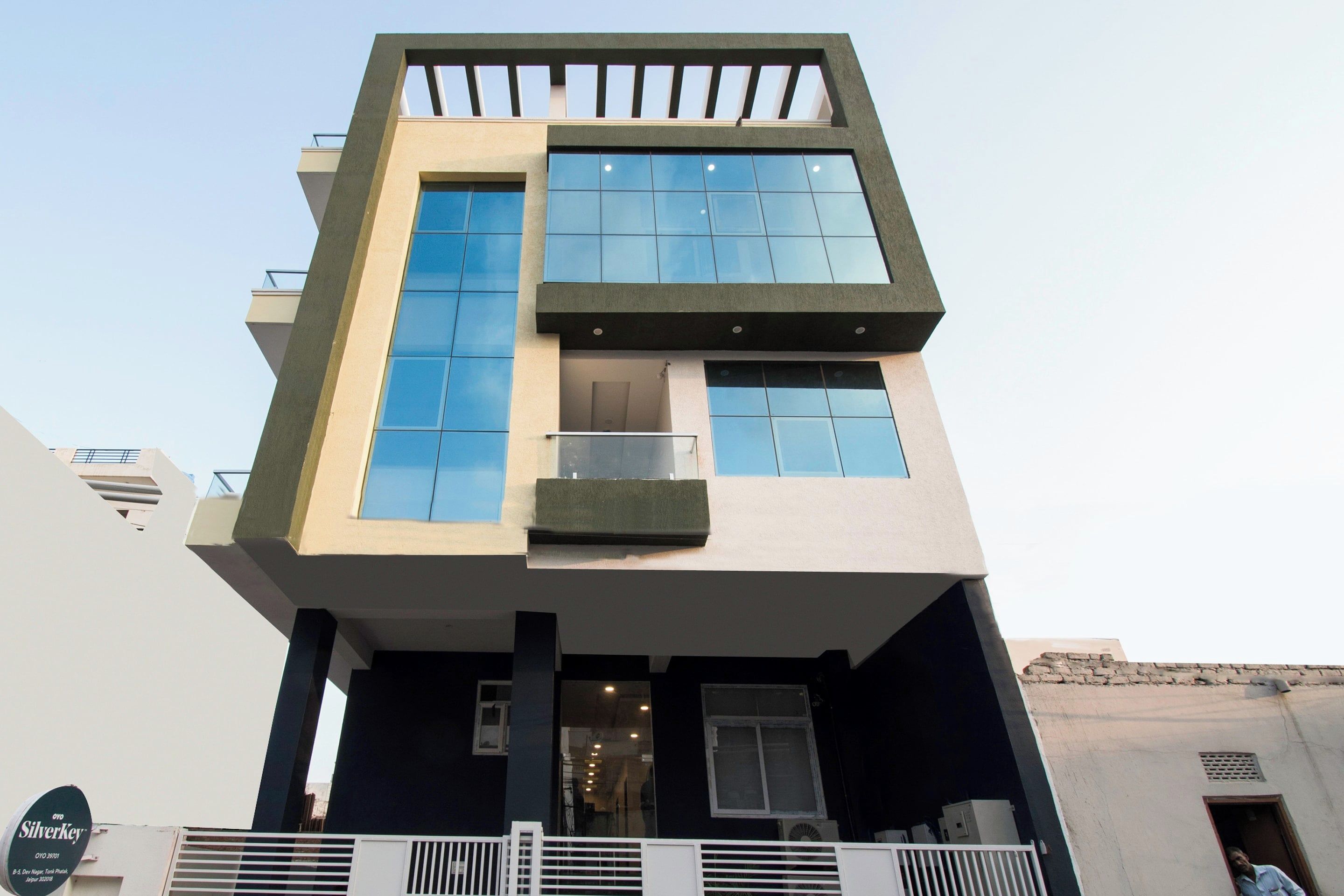 A modern building with a flat roof, large windows, and a balcony.