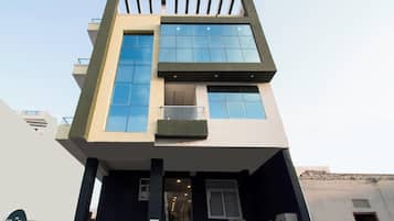 A modern building with a flat roof, large windows, and a balcony.