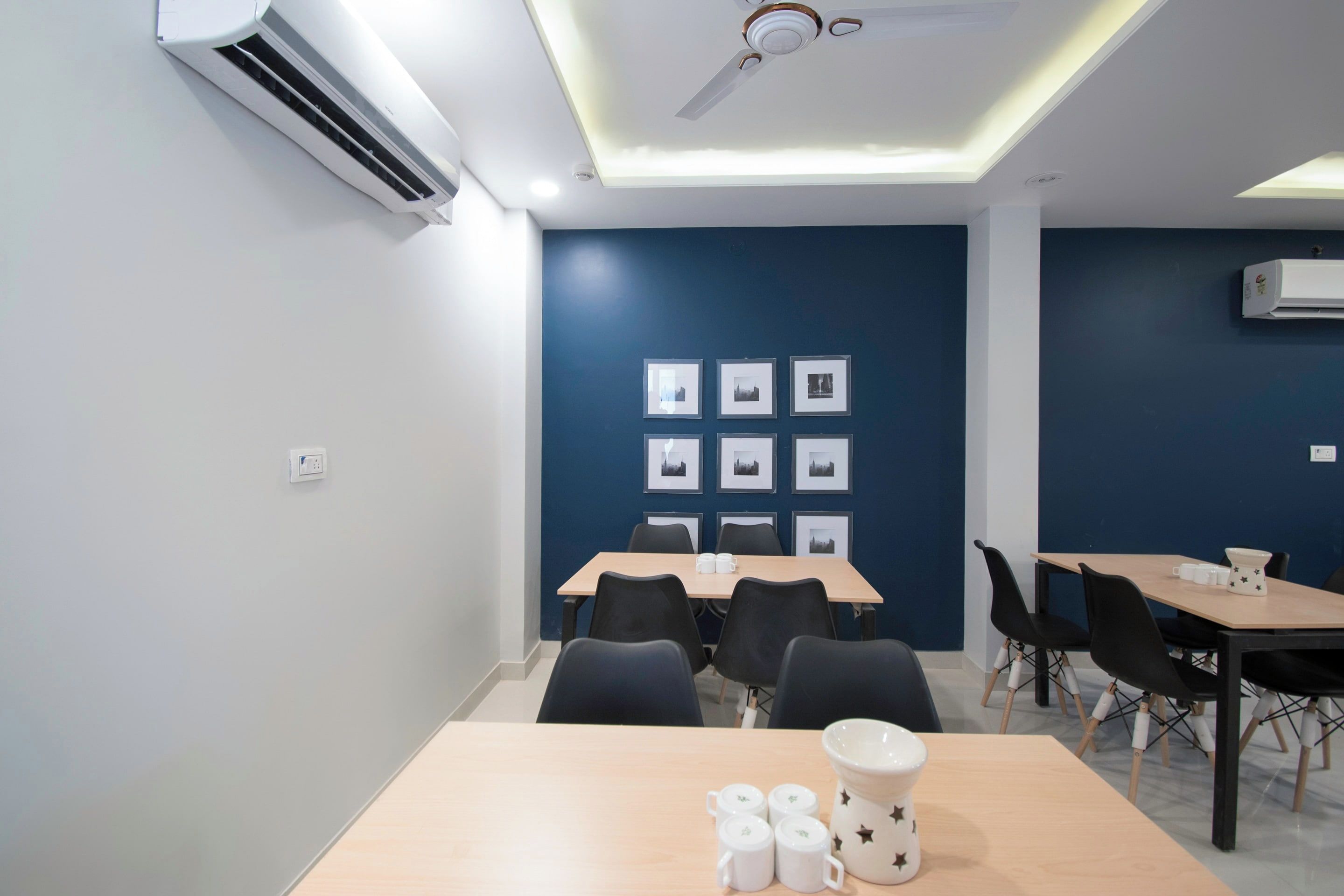 A conference room with tables, chairs, and framed pictures on the wall.