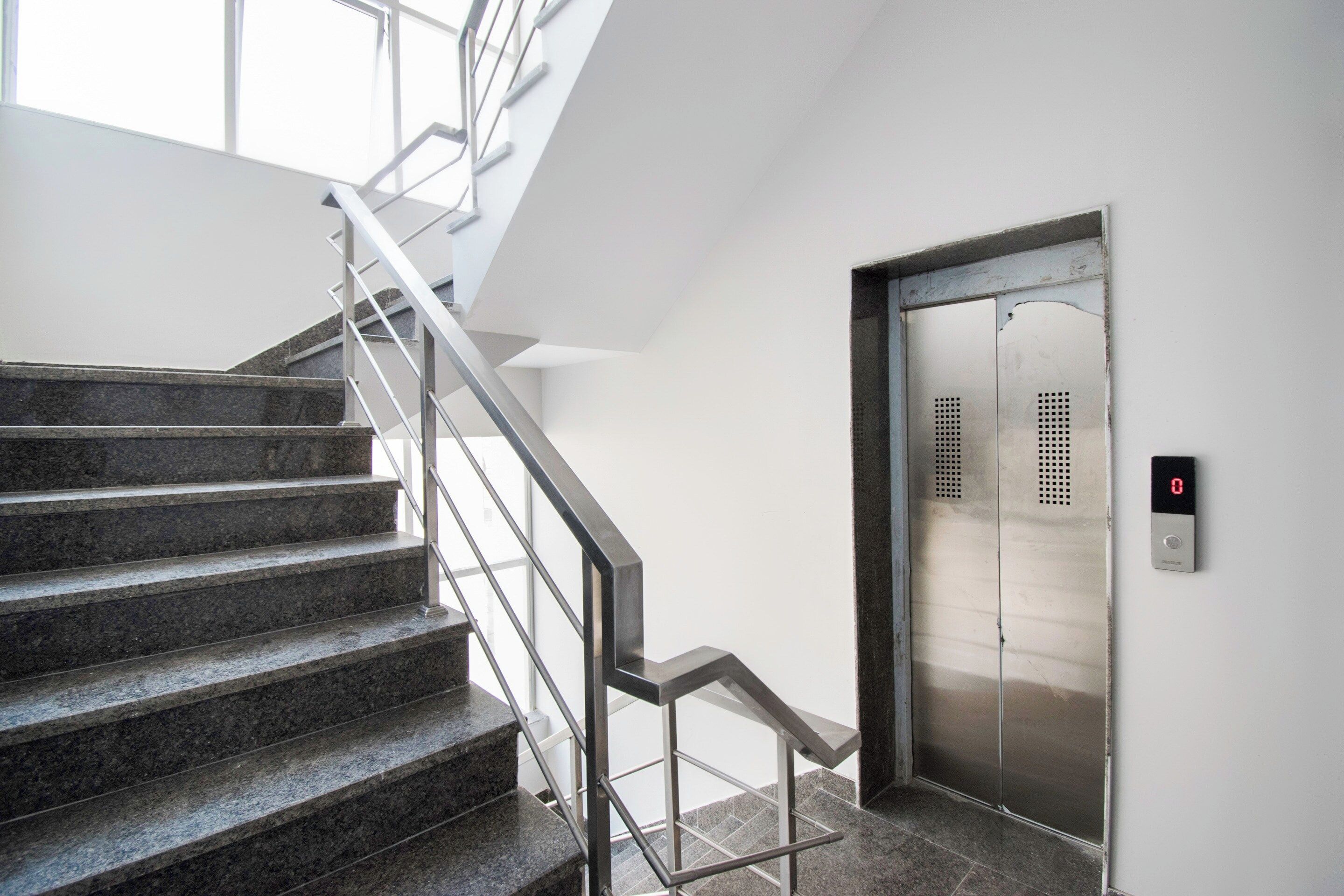 A modern staircase with metal railings leading to an elevator.