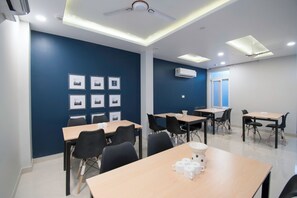 Un salón de conferencias con mesas, sillas e imágenes enmarcadas en la pared.