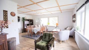 Amplia sala de estar con comedor, suelo de madera y techo alto con vigas a la vista.