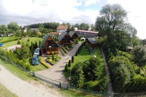 A row of cabins with a paved driveway leading to a parking area, surrounded by well-maintained greenery. - Holiday home in the Baltic Sea with 2 bedrooms (Mielenko \/ bei Mielno)
