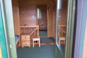 Ein Holzblockhaus-Interieur mit einem Bett, einem kleinen Schreibtisch und einem Stuhl.
