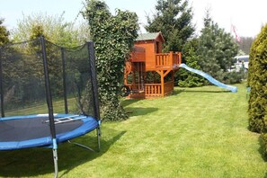 A trampoline and a wooden playhouse with a slide in a grassy yard. - Holiday home in the Baltic Sea with 2 bedrooms (Mielenko \/ bei Mielno)