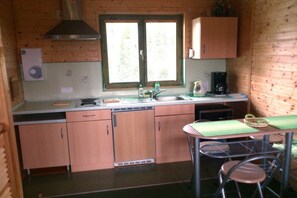 A compact kitchen with wooden cabinets, a sink, a stove, and a window with blinds. - Holiday home in the Baltic Sea with 2 bedrooms (Mielenko \/ bei Mielno)