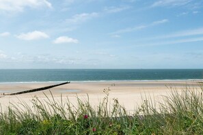 A beach with a wooden jetty, clear sky, and calm sea. - Groepshuis Oase (12 people) (Zoutelande)