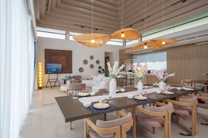 Un espace repas moderne avec une longue table dressée pour un repas, entourée de chaises.