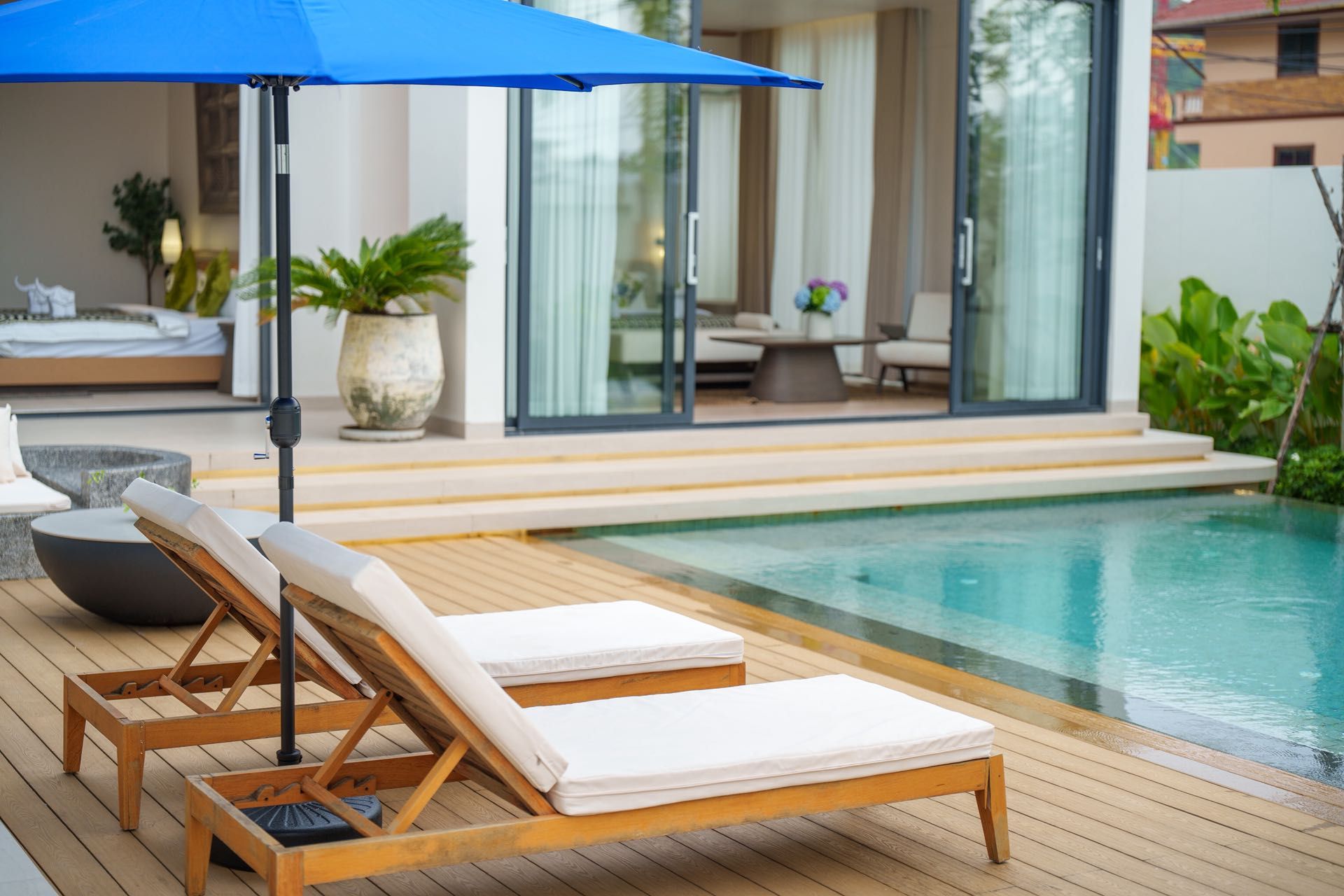 A poolside area with wooden loungers and a blue umbrella.