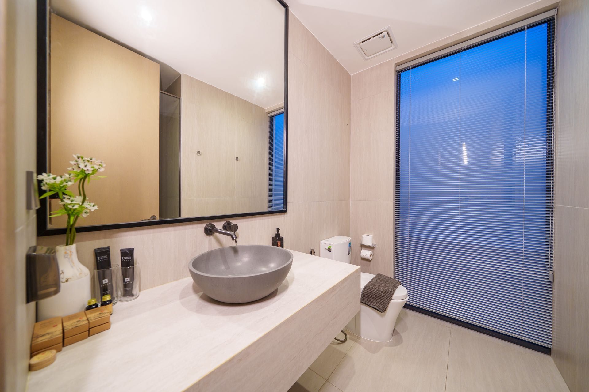 A modern bathroom with a large mirror, a bowl sink, and a toilet.