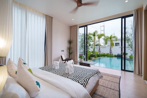 Une chambre d’hôtel avec un grand lit, un bureau, une chaise, une vue sur la piscine et un ventilateur de plafond.