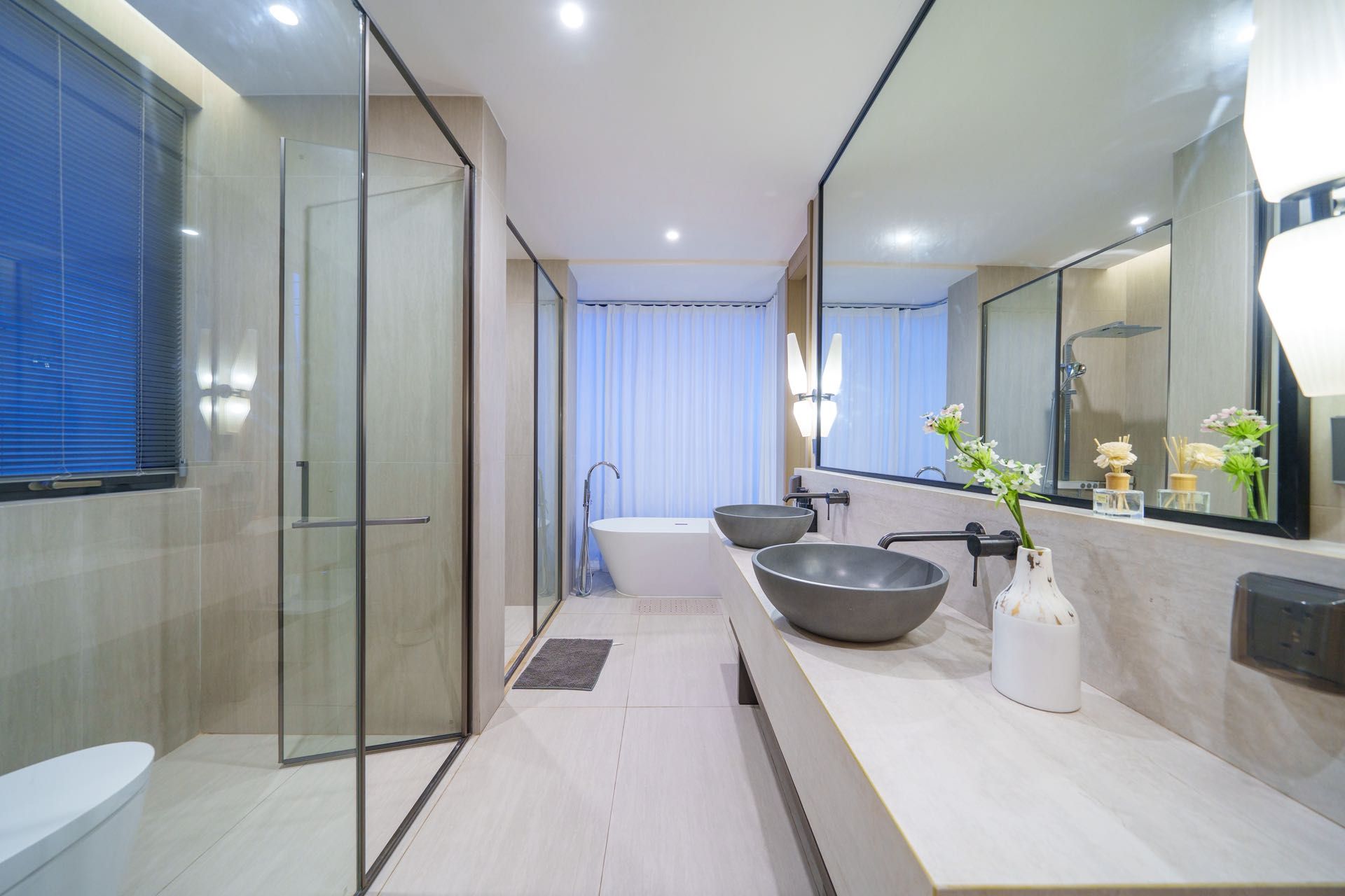 Un baño moderno con cabina de ducha de vidrio, una bañera y un lavabo doble.