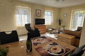 A dining area with a table set for two, a television, a sofa, and a plant. - Holiday apartment with 1 bedroom (Bernkastel-Kues)